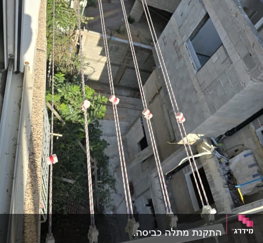 מתקן כביסה עם חבלים וגלגלות על קיר חיצוני